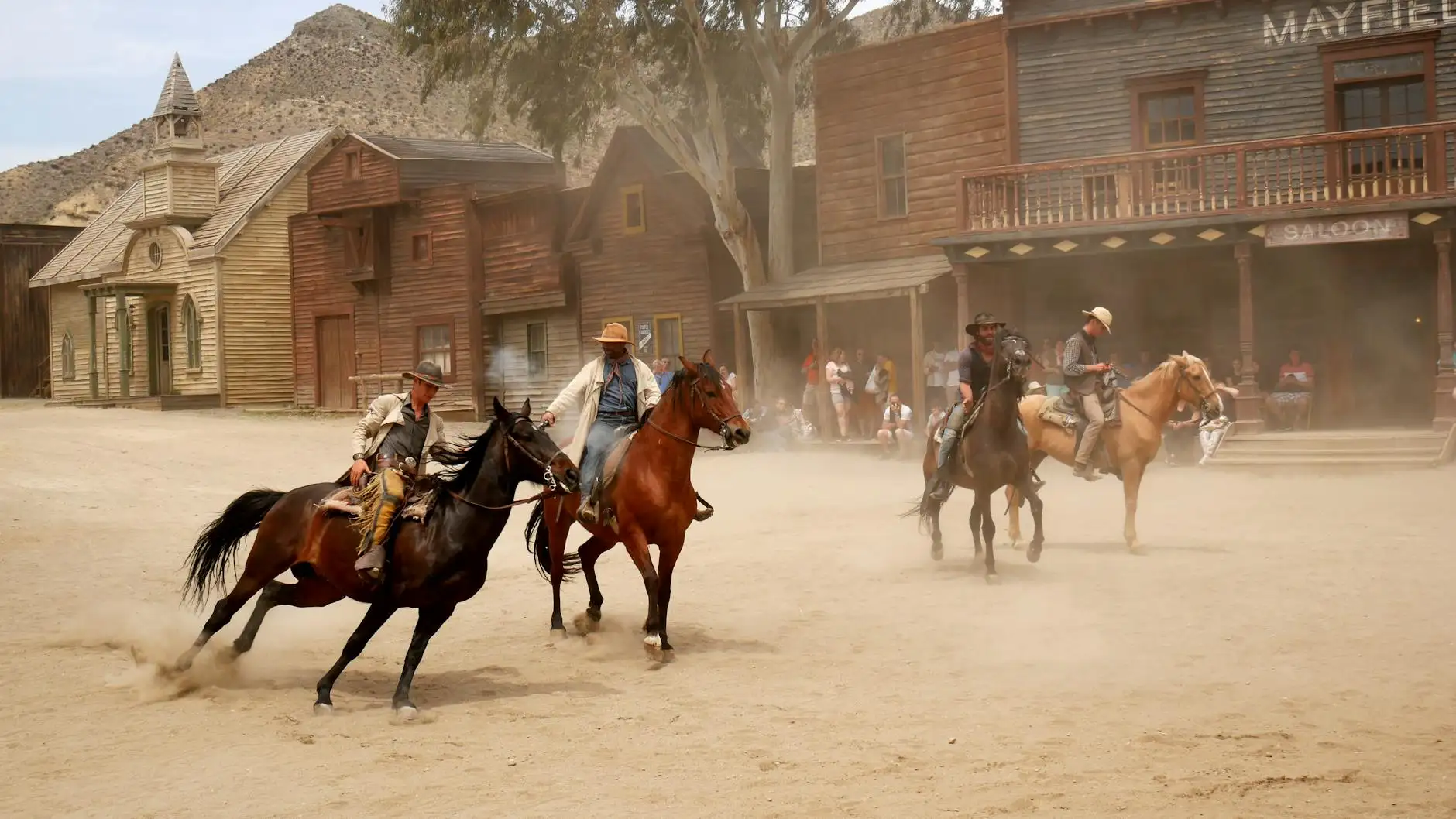 Cowboys on horseback perform reenactment in a Wild West town setting at Almería, Spain.