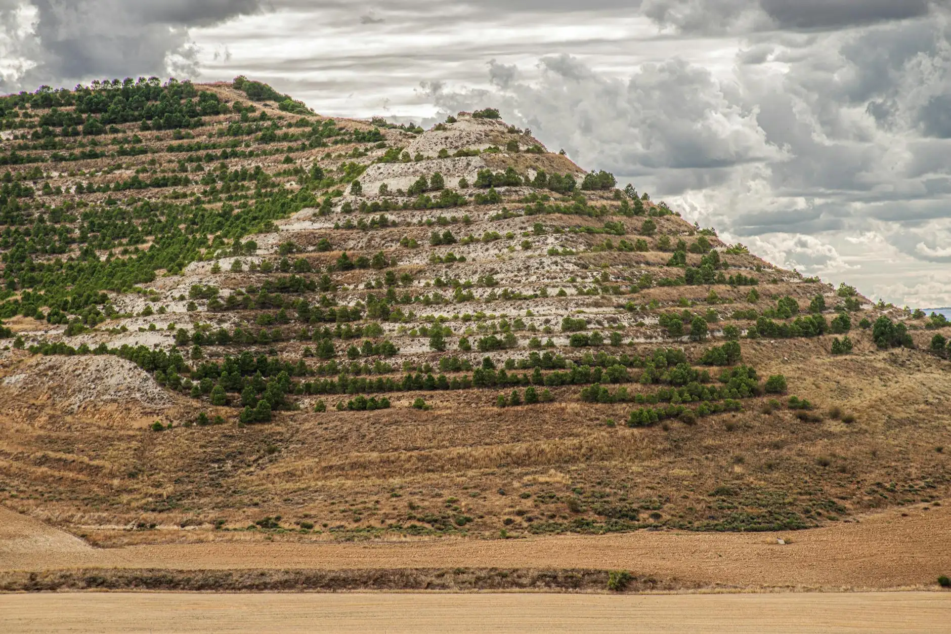 A breathtaking view of terraced hills under a dramatic cloudy sky in Soto de Cerrato, Spain.