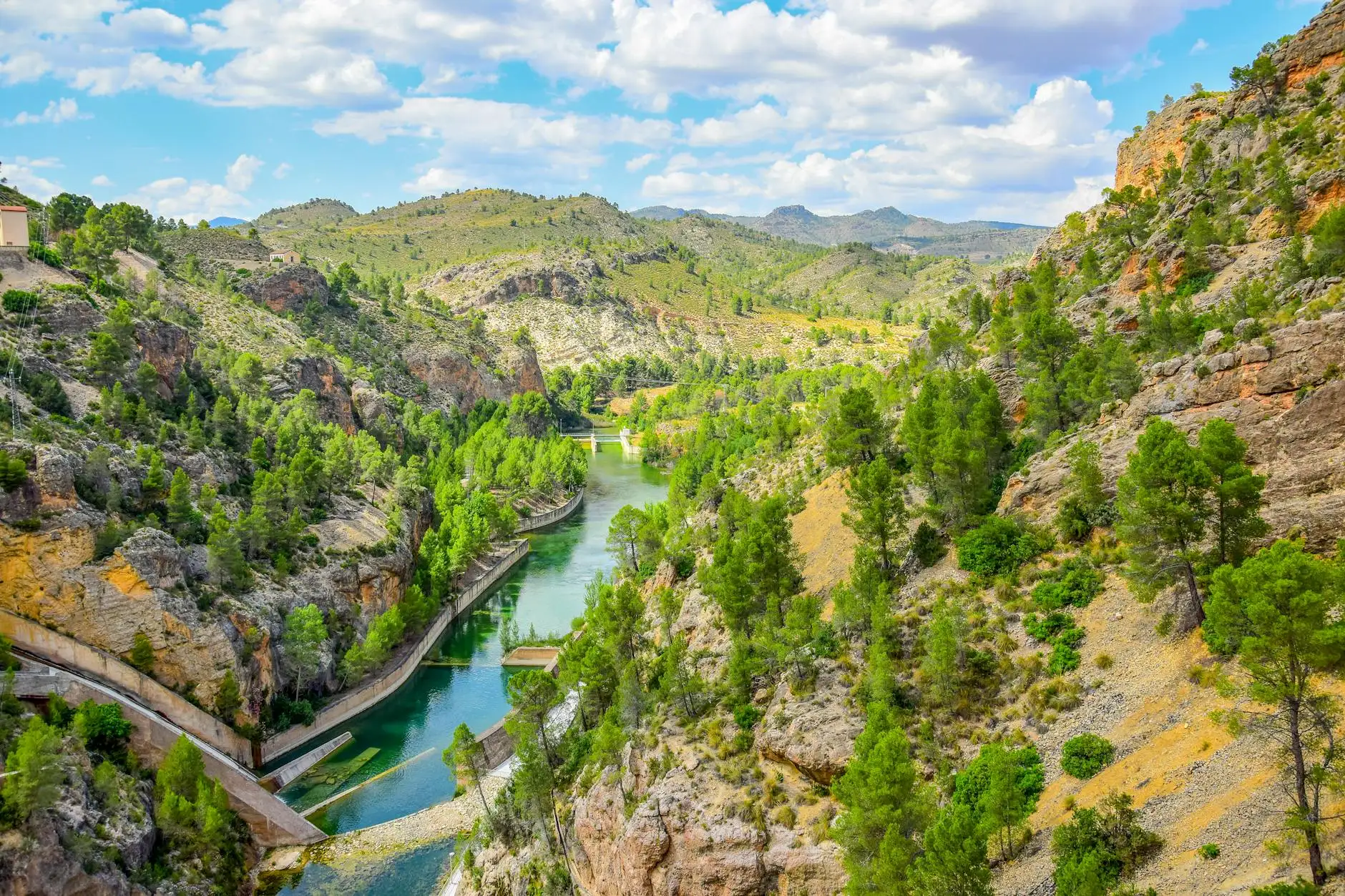 Aerial view of the lush river landscape in Yeste, Spain, with hills and clouds.