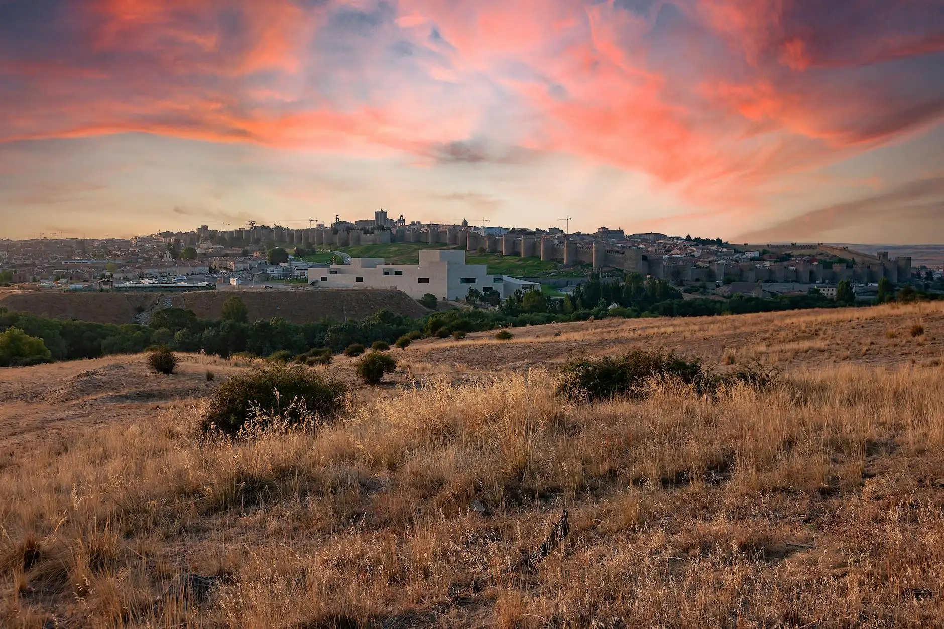 Beautiful sunset over Ávila's ancient city walls, with a sprawling landscape in view.