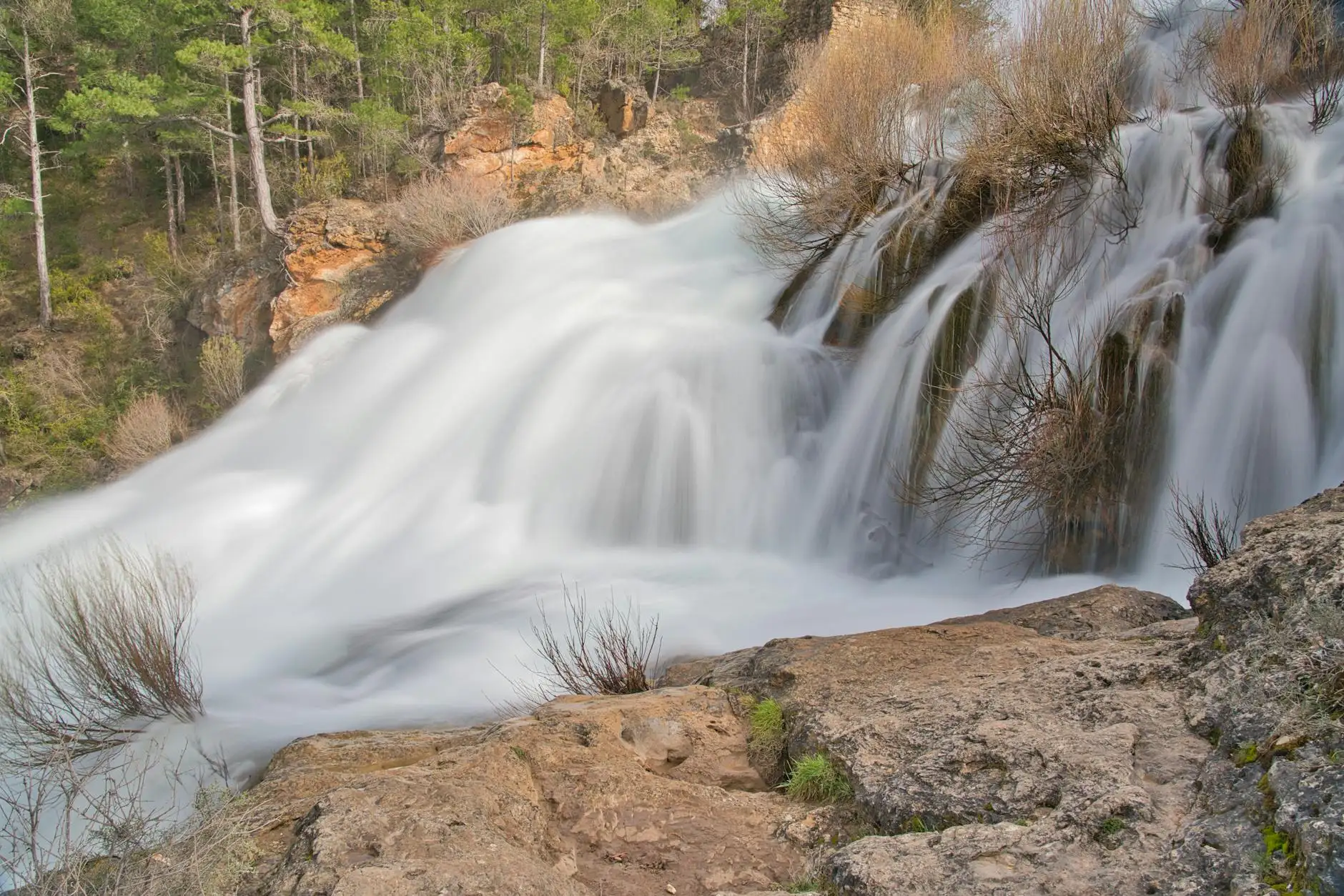 Beautiful long exposure of a waterfall in Guadalajara, Spain, surrounded by lush green trees.
