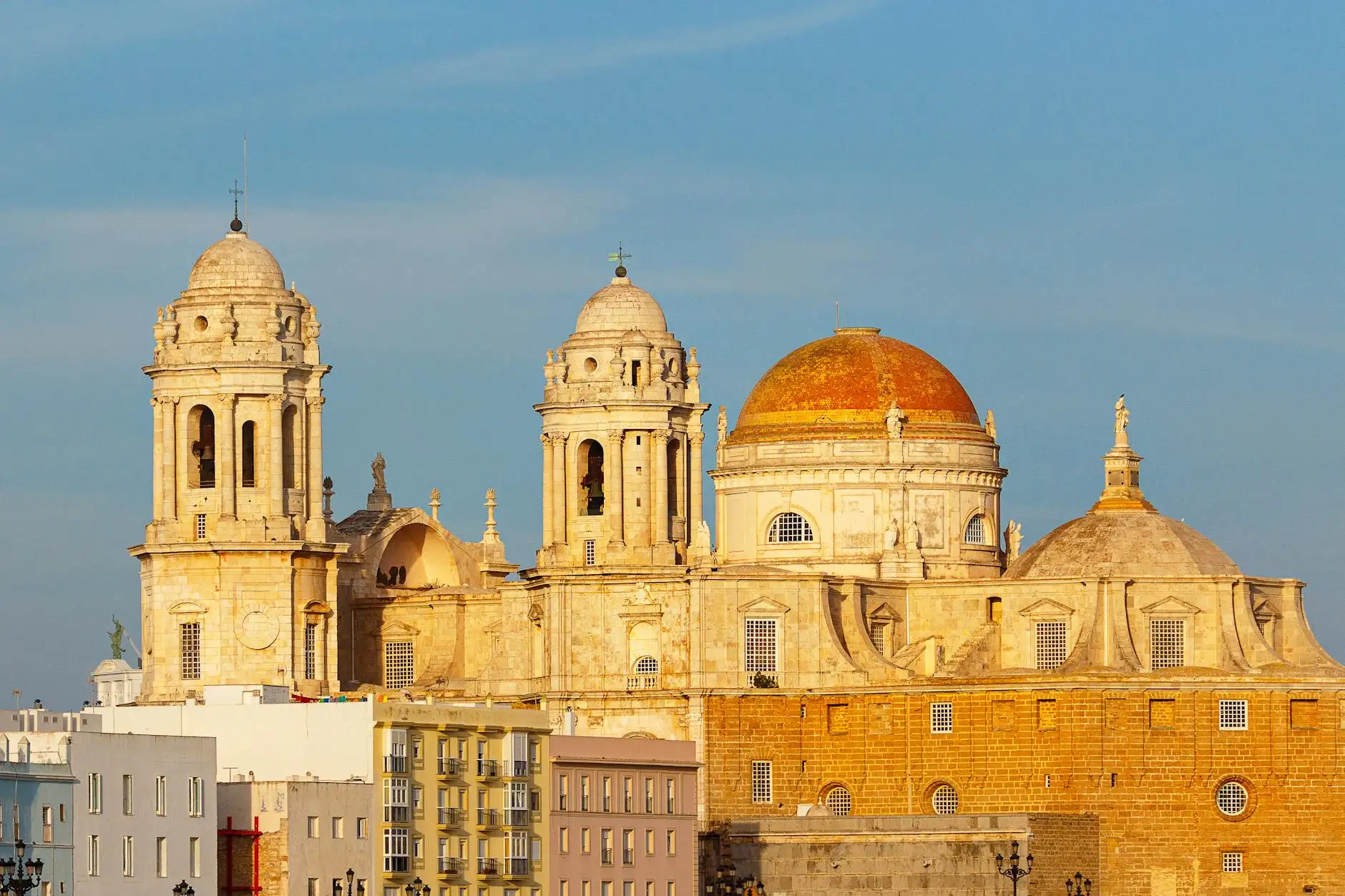 A picturesque capture of the Cadiz Cathedral in Spain during sunset with a golden hue.