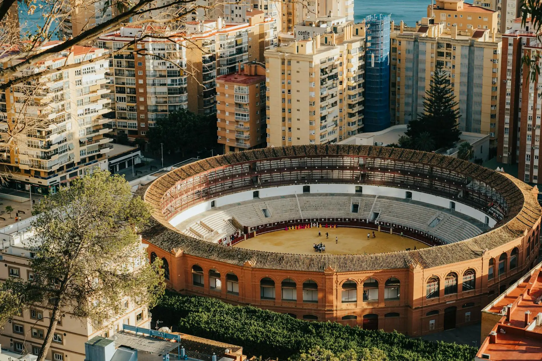 Stunning aerial view of the Málaga bullring surrounded by cityscape and Mediterranean Sea.