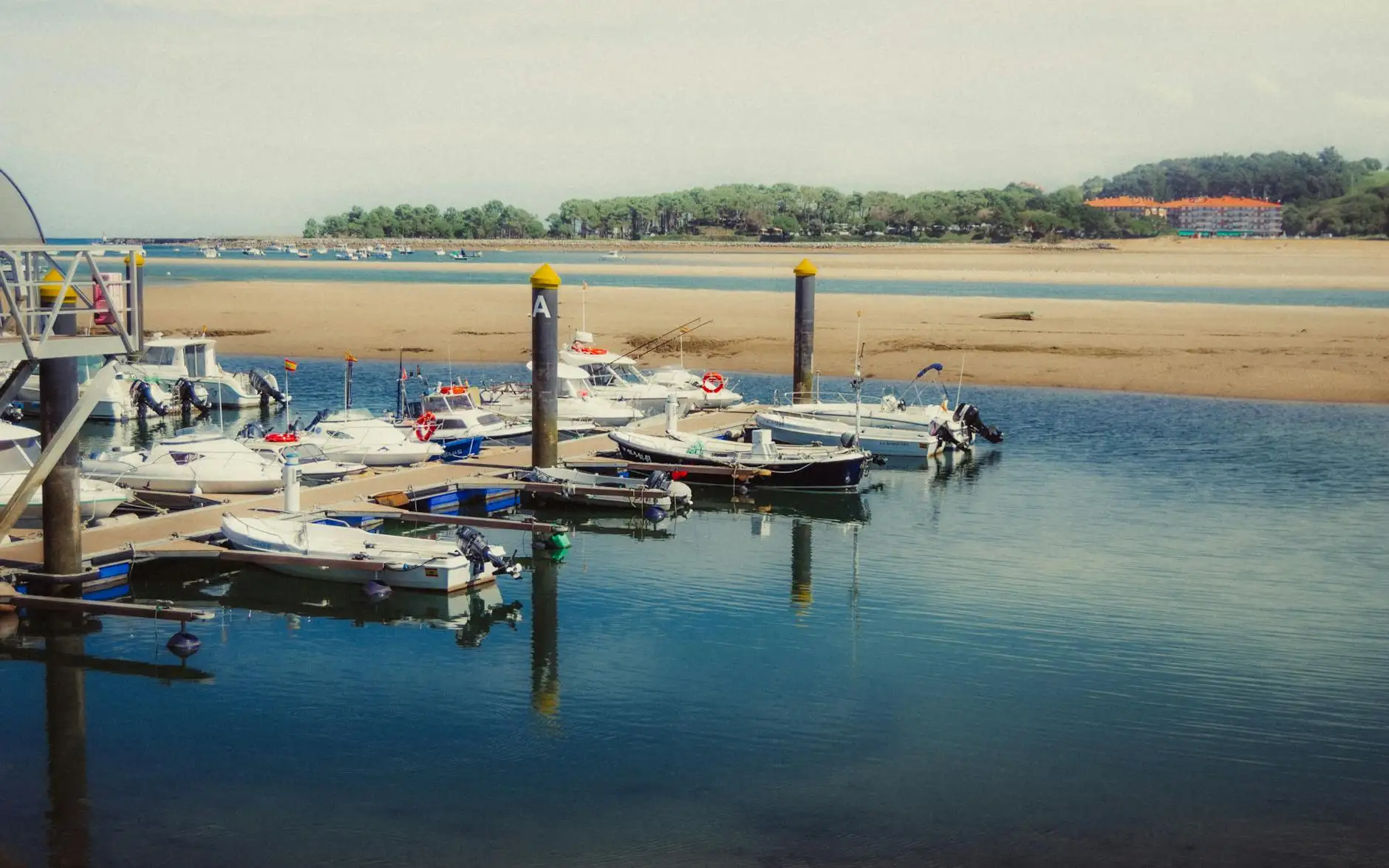 Boats docked at a serene marina in Asturias, Spain, with a picturesque coastline view.