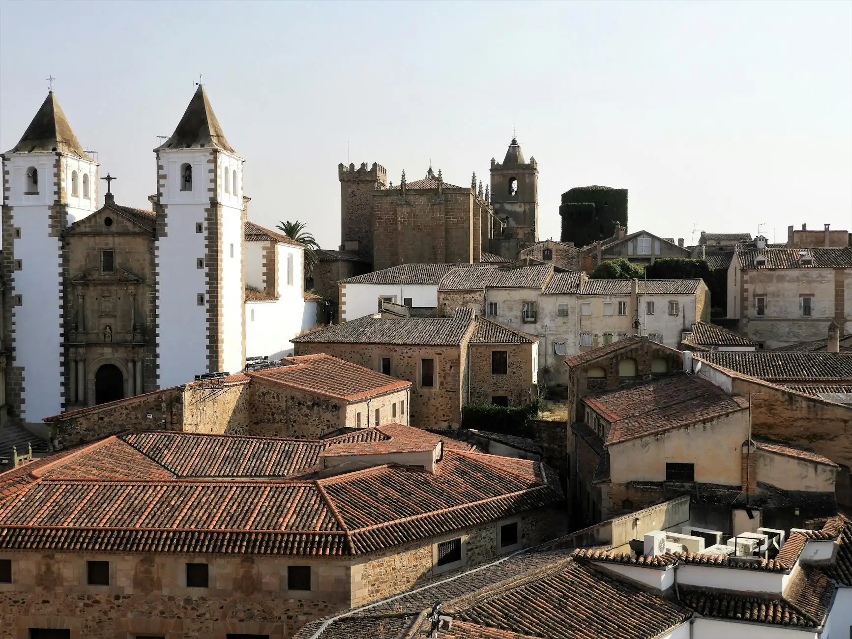 Aerial view of the historic architecture of Cáceres, Spain showcasing old stone buildings and churches.